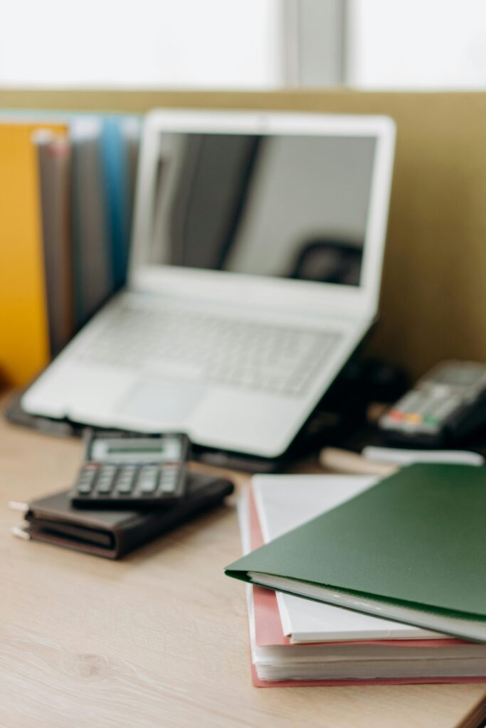 A tidy office desk setup featuring a laptop, calculator, and folders for efficient work.